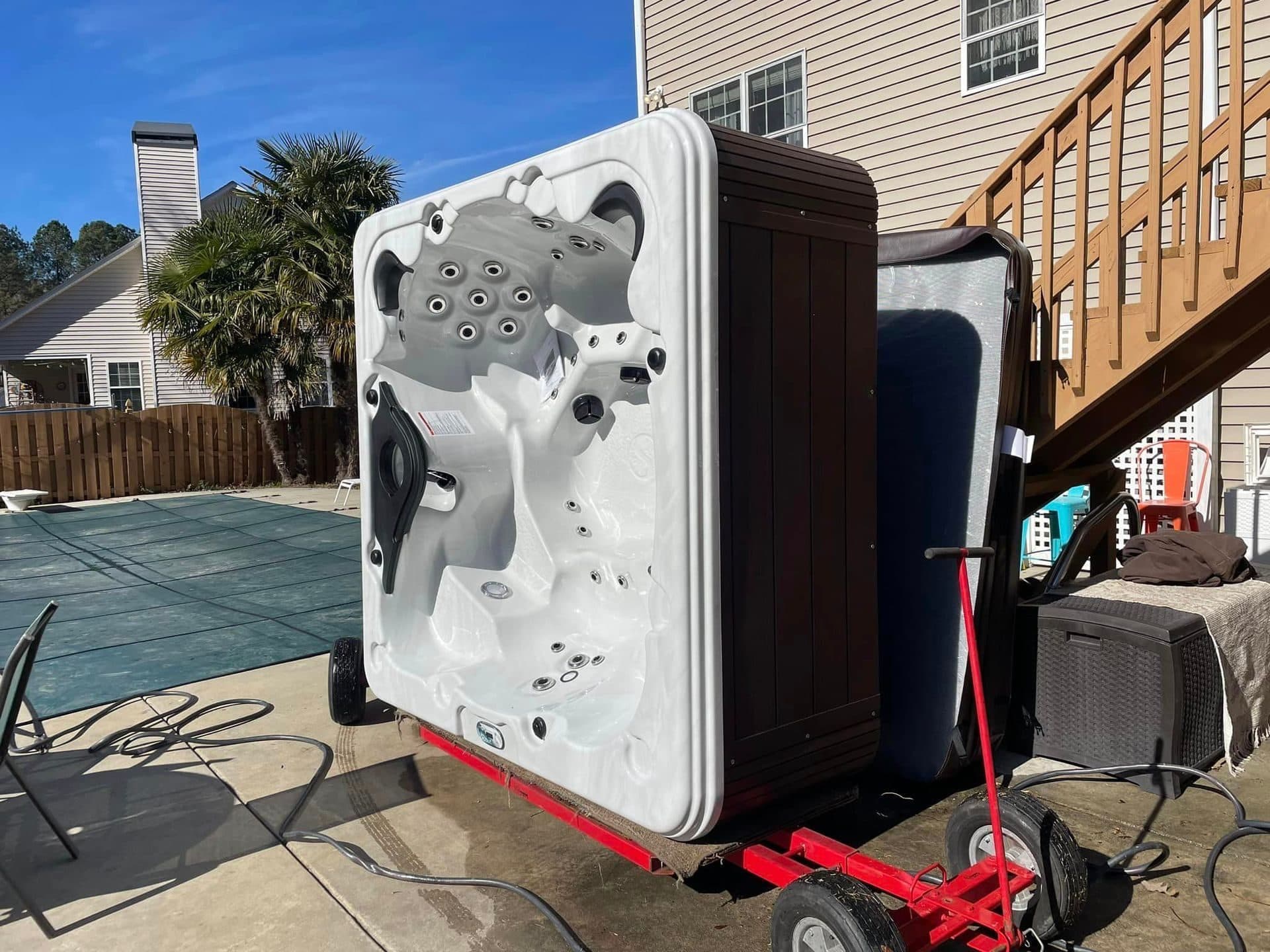 A clean white hot tub secured upright on a moving dolly